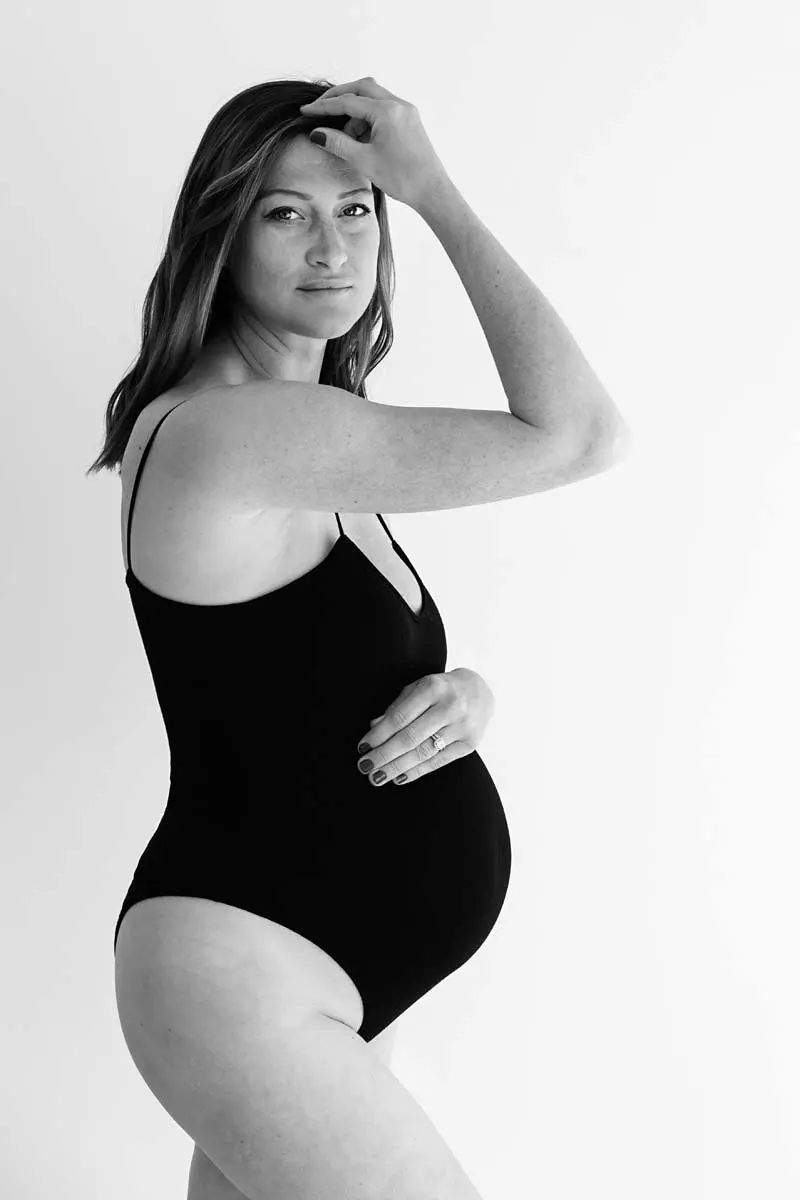 black-and-white-photo.-Profile-of-pregnant-mum.-She-is-wearing-a-black-bodysuit-and-looking-at-the-camera.-Photo-taken-during-a-photoshoot