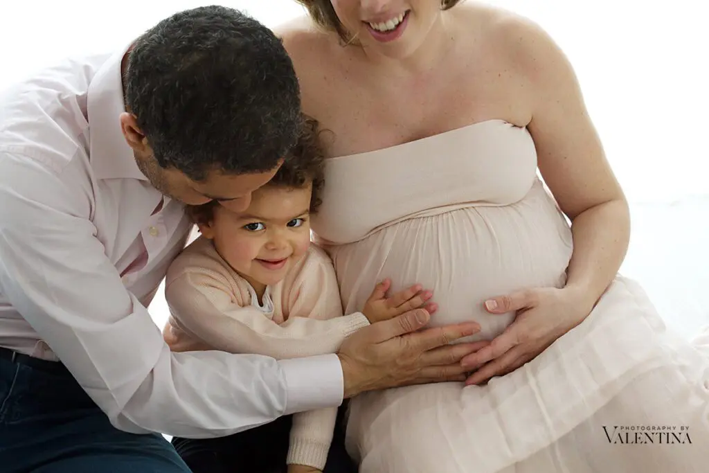 soulful family portrait - mum is pregnant and dad and sister are touching the baby belly