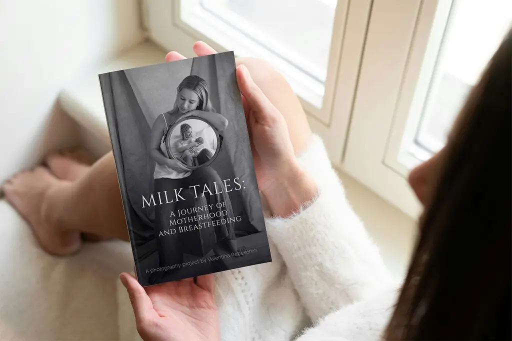 Close-up of a woman holding Milk Tales, a breastfeeding photography book by Valentina Rebeschini, featuring real stories and portraits of motherhood.