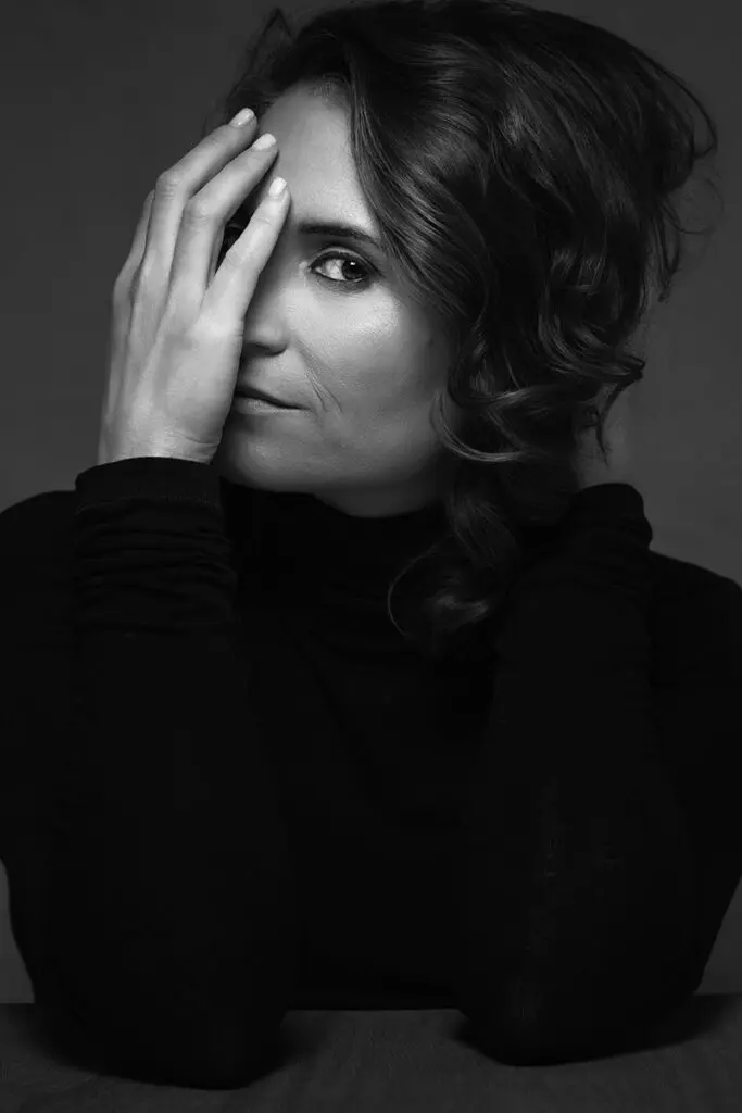 Black-and-white portrait of a woman with her hand resting against her face, the kind of honest image that gets at why do I hate photos of myself