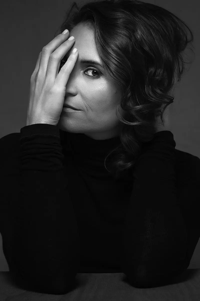 Black-and-white portrait of a woman with her hand resting against her face, the kind of honest image that gets at why do I hate photos of myself