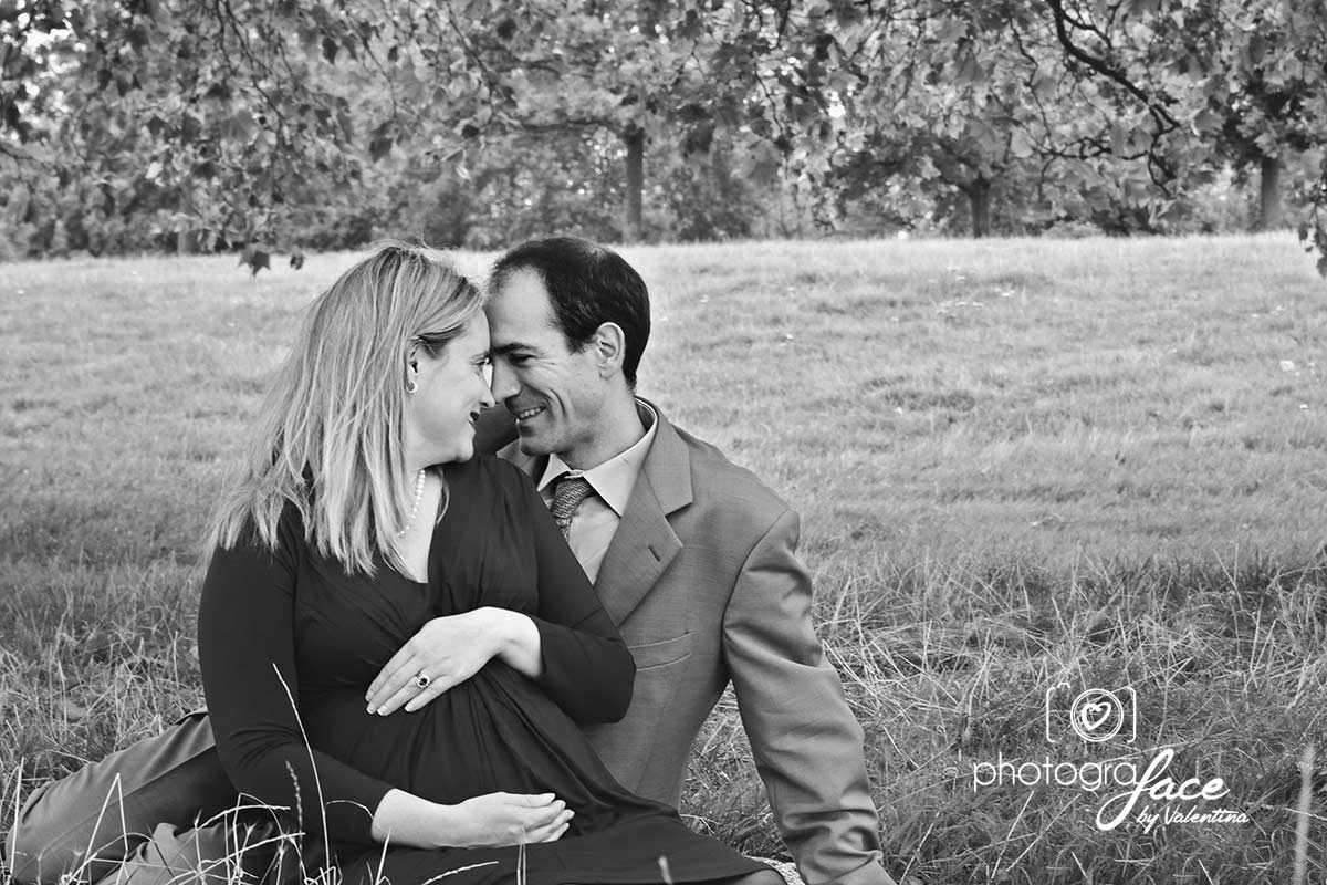 black and white portrait of couple sitting and looking at each other in a park