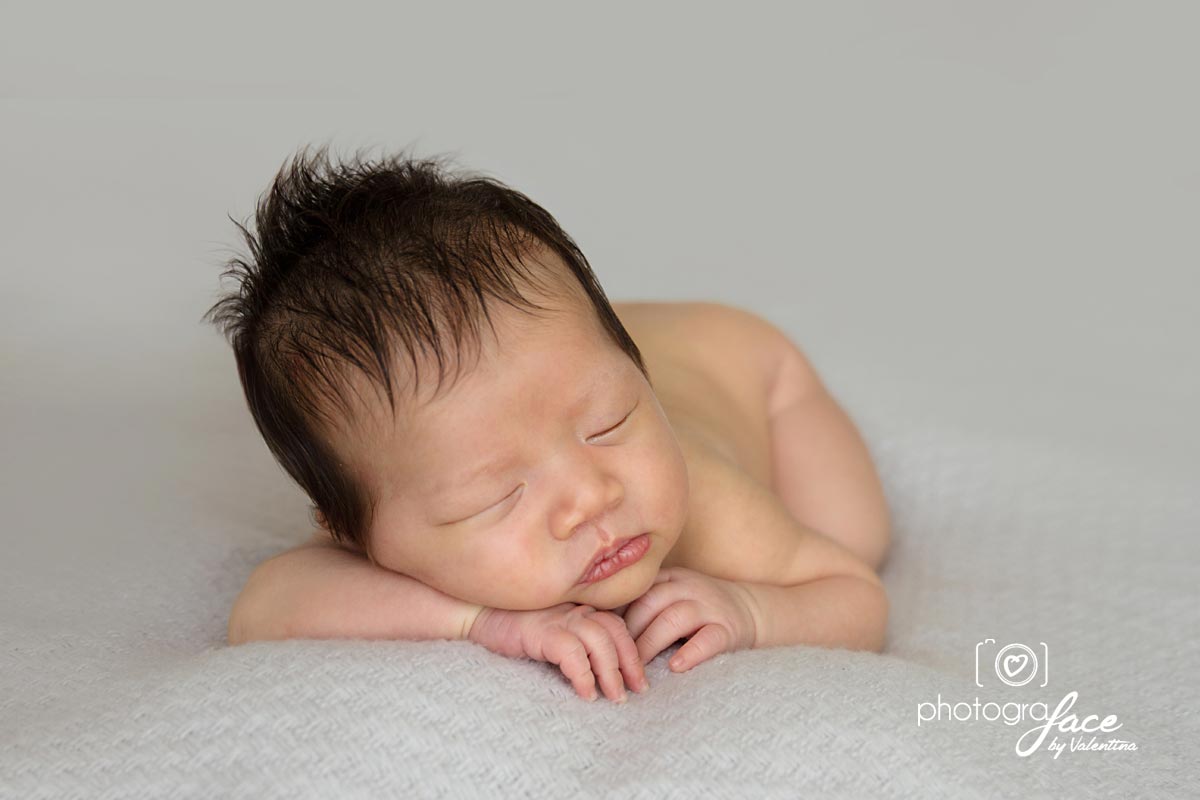 Asian baby sleeping on his tummy with hands under chin pose during a newborn photoshoot