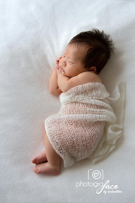 newborn sleeping on his side with a soft wrap on top