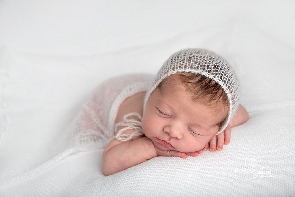 newborn photography: baby girl sleeping on her tummy on a white blanket