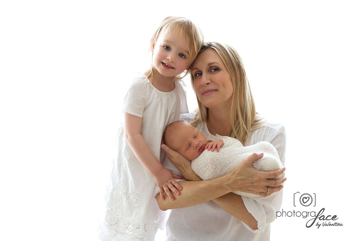 What to wear: white is always a goos choice. Mum holding newborn baby on a white top and bigger girl on a white dress
