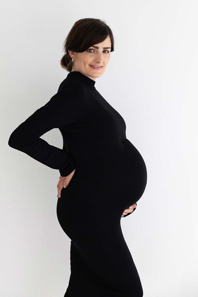 Profile of pregnant mum wearing a black stretchy dress. Photo taken during a maternity photoshoot in Twickenham