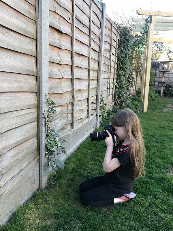photography games for children: girl photographing an item from a photo scavenger hunt.