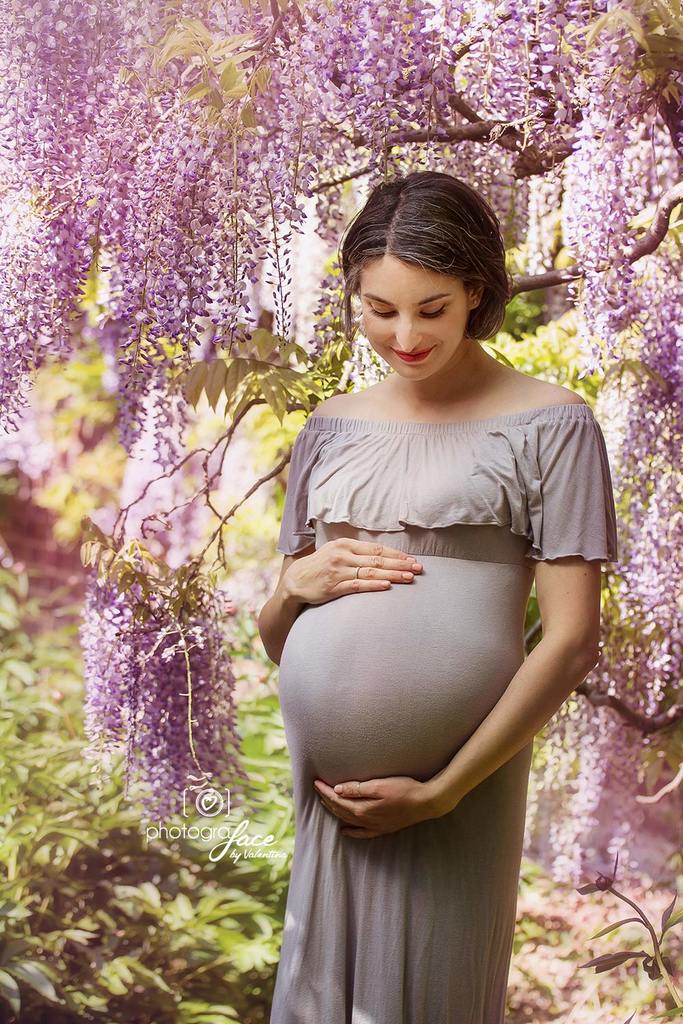 portrait of expecting mum wearing a grey dress surrounded by wisteria - outdoor photography London maternity session