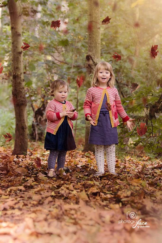 sisters in a park throwing autumn leaves
