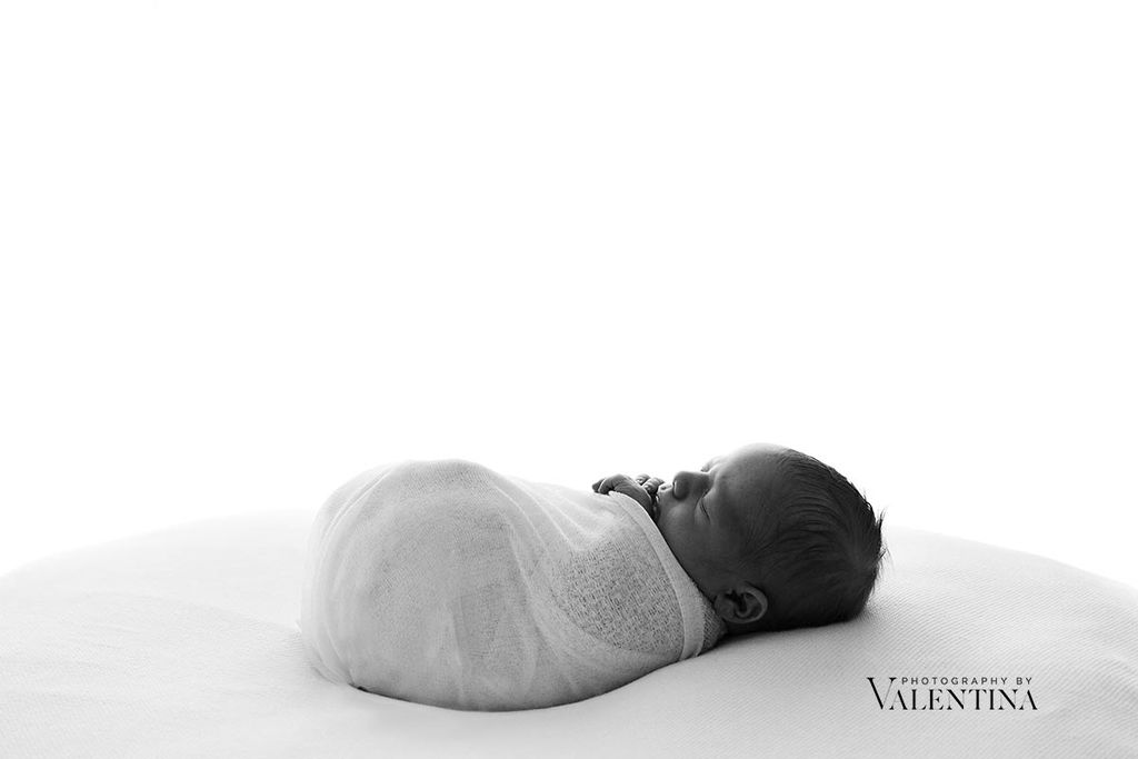 Baby safety. Black and white image of sleeping newborn on a beanbag with white blanket.