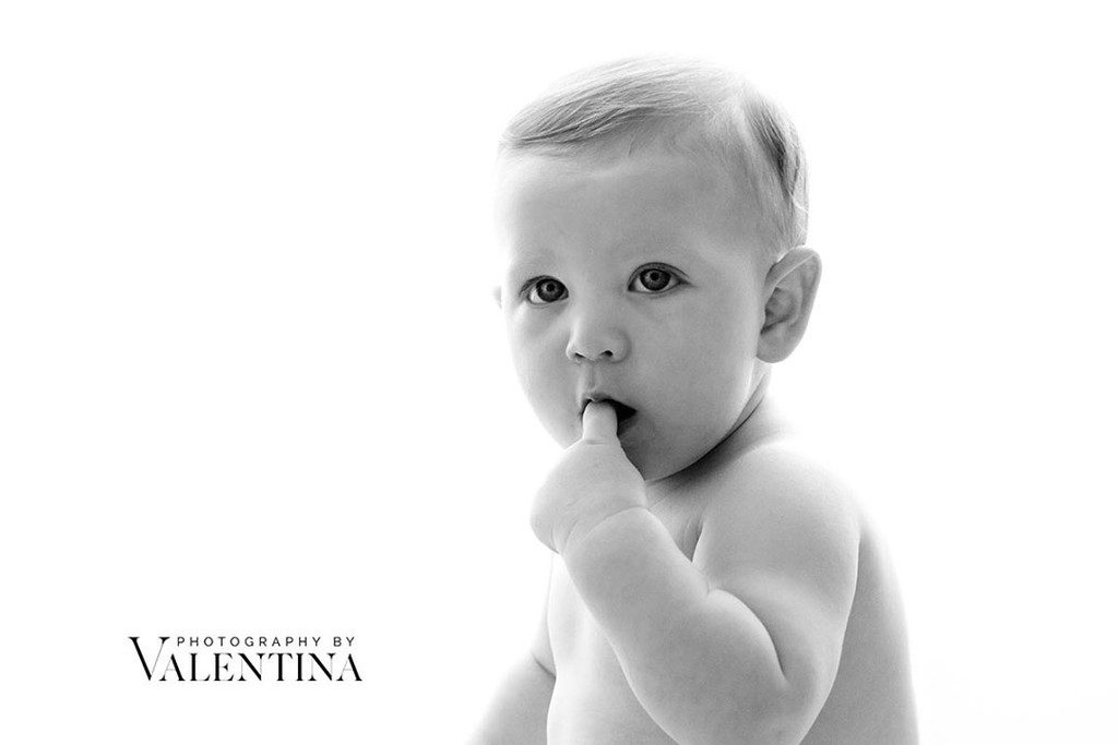 black and white image of baby boy  sucking his finger. 