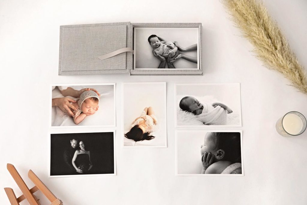 aerial shot of a grey box of prints and some printed photos of newborns laying around.