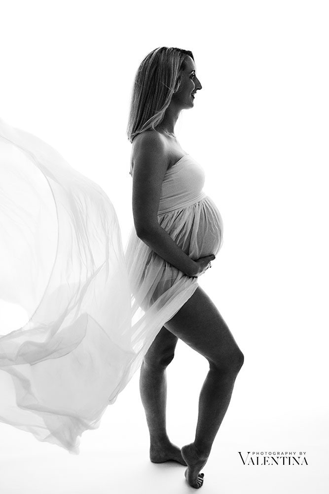 silhouette of a pregnant woman. black and white image on a white background. Mum is wearing a floaty and see-through dress