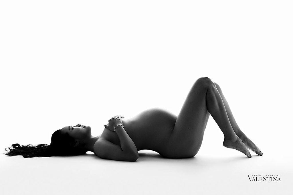 black and white image of a pregnant woman naked on the the floor - maternity photography