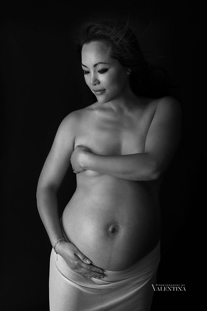 black and white image of maternity. Mum holds her arm around the naked breast