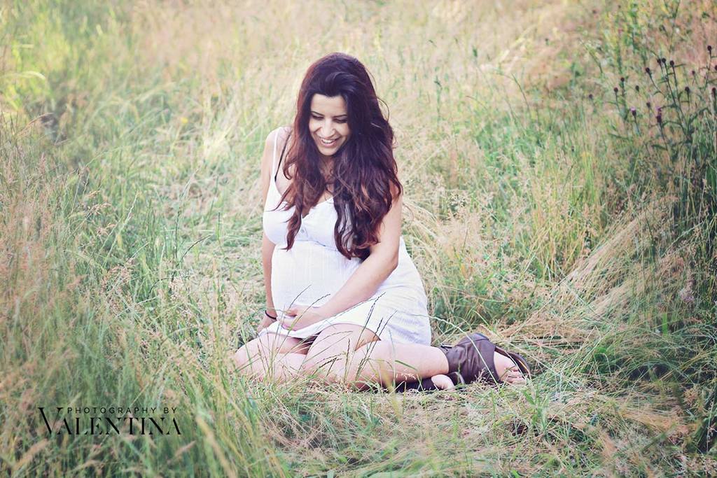 beautiful photo of pregnant mum sitting on long grass wearing a white dress.