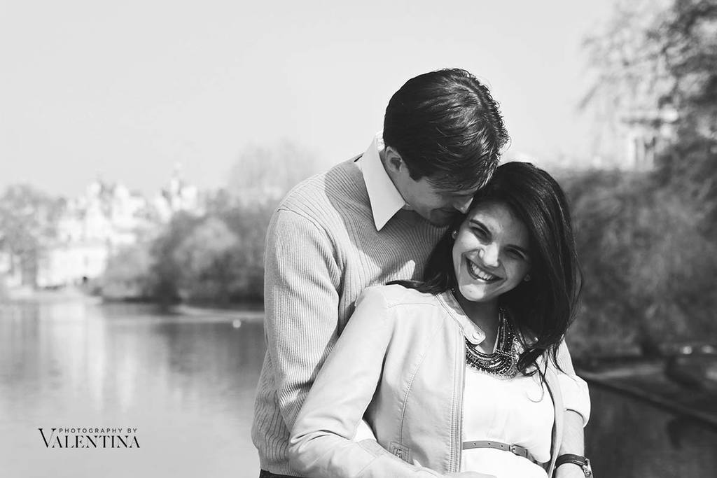 black and white image of pregnant couple. Dad is hugging mum from behind. 