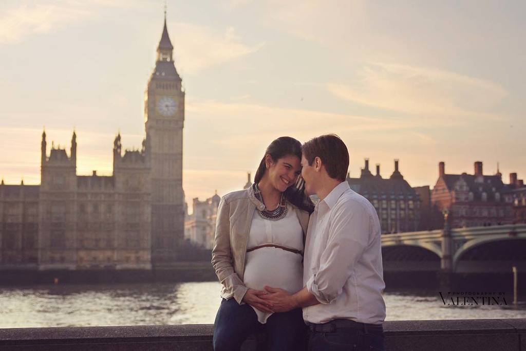 portrait of pregnant couple looking at each other in front of the big ben at sunset