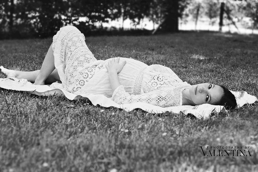 Black and white image of pregnant woman laying on the grass during an outdoor pregnancy shoot