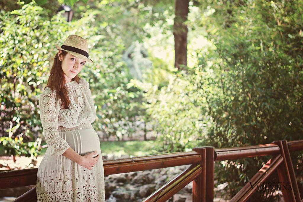 Pregnant mum standing by a wooden bridge by a lake