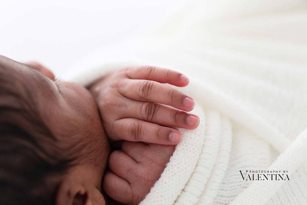 macro photography: image of newborn hands under baby's chin