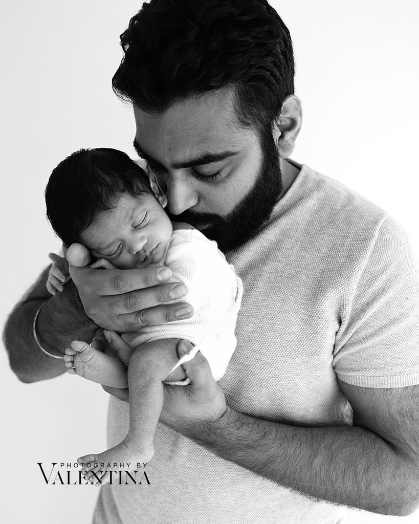 dad is holding newborn baby on his hands and giving him a little kiss