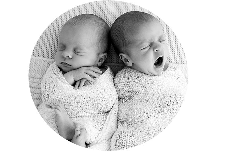 black and white portrait of newborn tweens wrapped in a white swaddle. Photo taken during a newborn photoshoot in London
