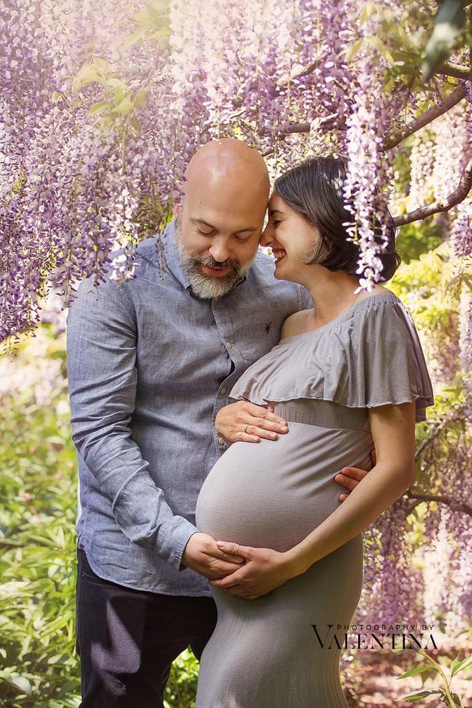 Outdoor maternity photoshoot. Pregnant couple surrounded by wisteria.