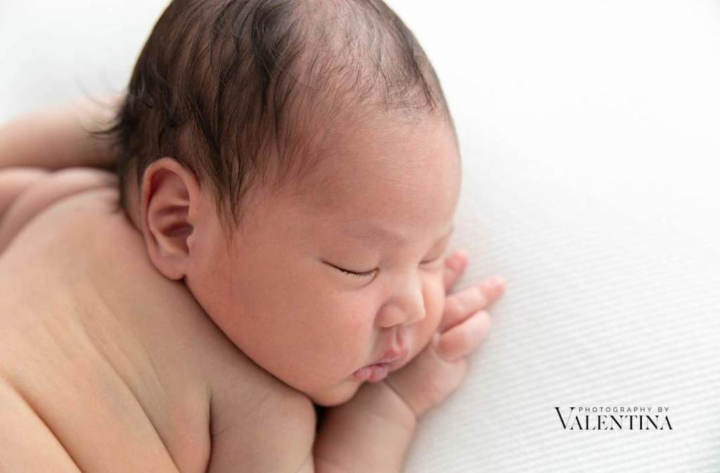 close up profile of newborn baby laying on a white blanket during a photoshoot