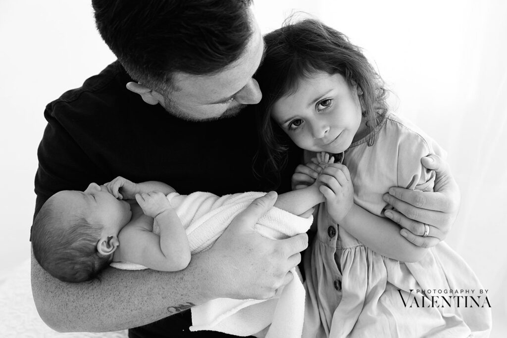 Black and white portrait of dad and his girls during a newborn photoshoot in London. 