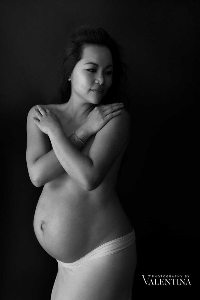 maternity photo - mum is naked and has her hands on her chest to cover it. 