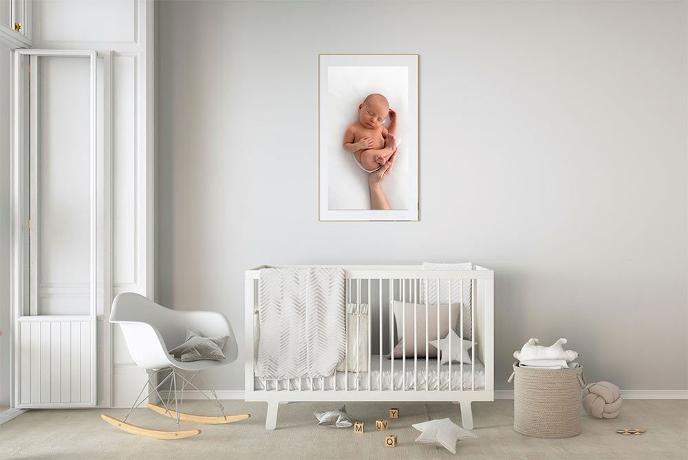 baby nursery room with a white cot and a beautiful newborn photo framed on the wall