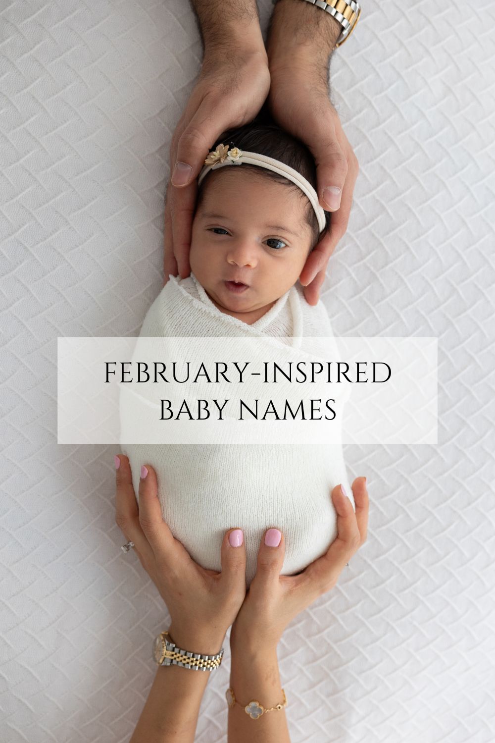 baby wrapped in a white swaddle and parents' hands are holding her. Title written on the image: february-inspired baby names