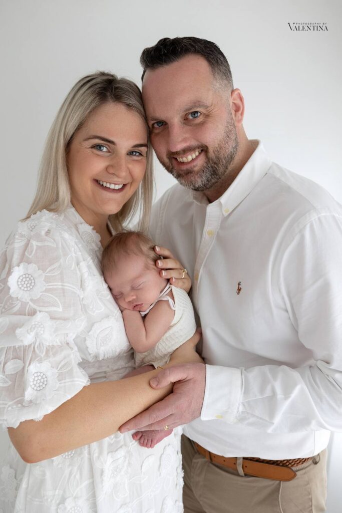 portrait of mum and dad holding newborn girl during a newborn photoshoot in London