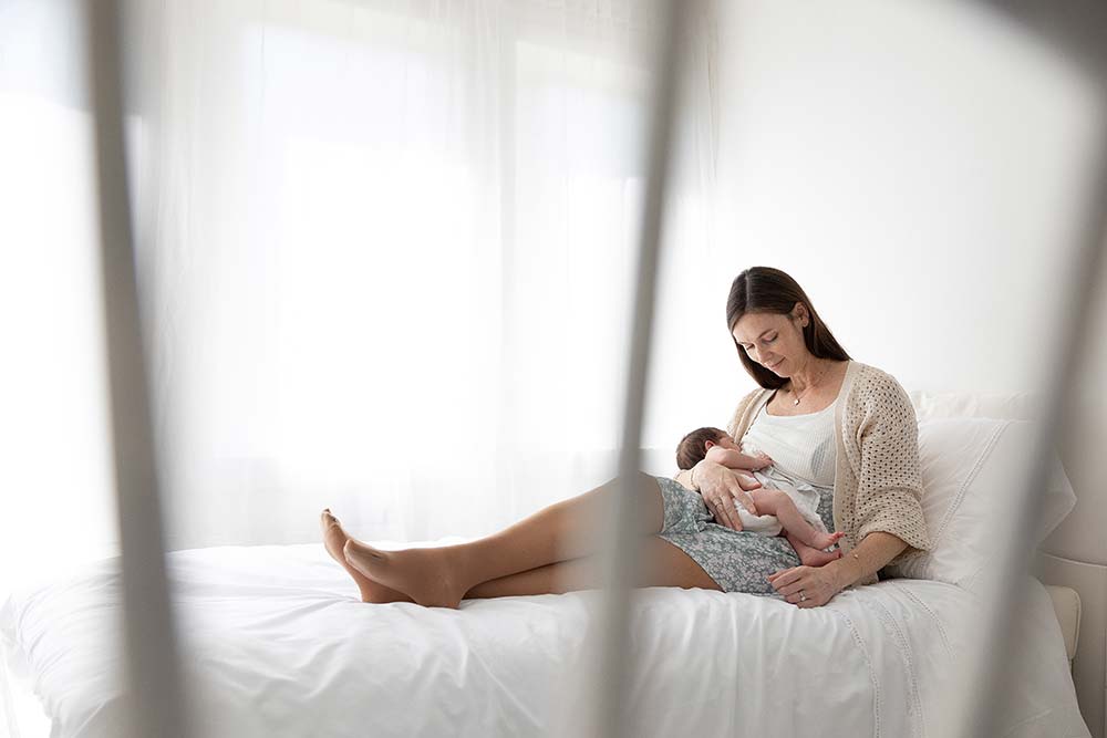 Mother breastfeeding newborn baby during photography session capturing bonding moment in London studio