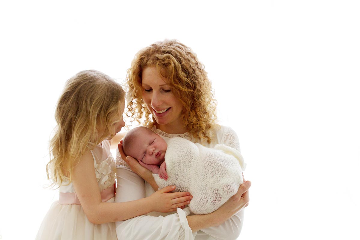 what to wear during a newborn session: mum with her girls dressed in white